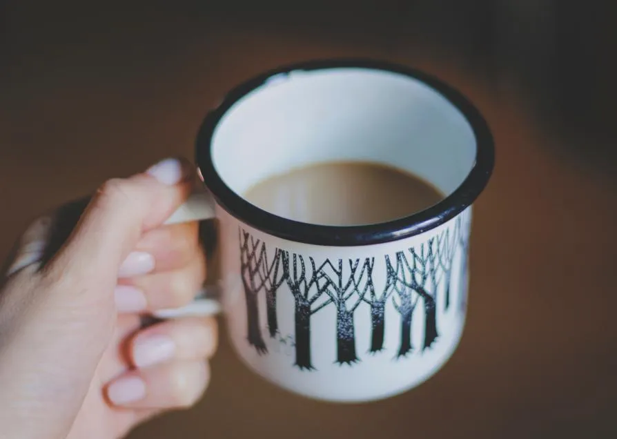 Hands holding an enamel mug